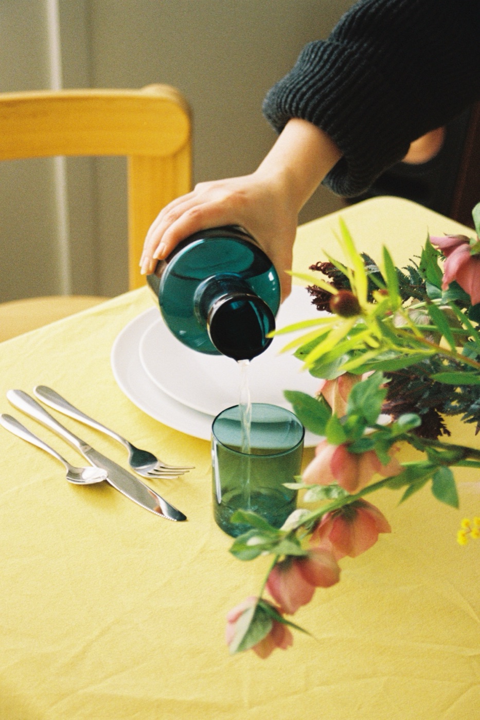 Pouring water into a glass tumbler at a table set with flowers