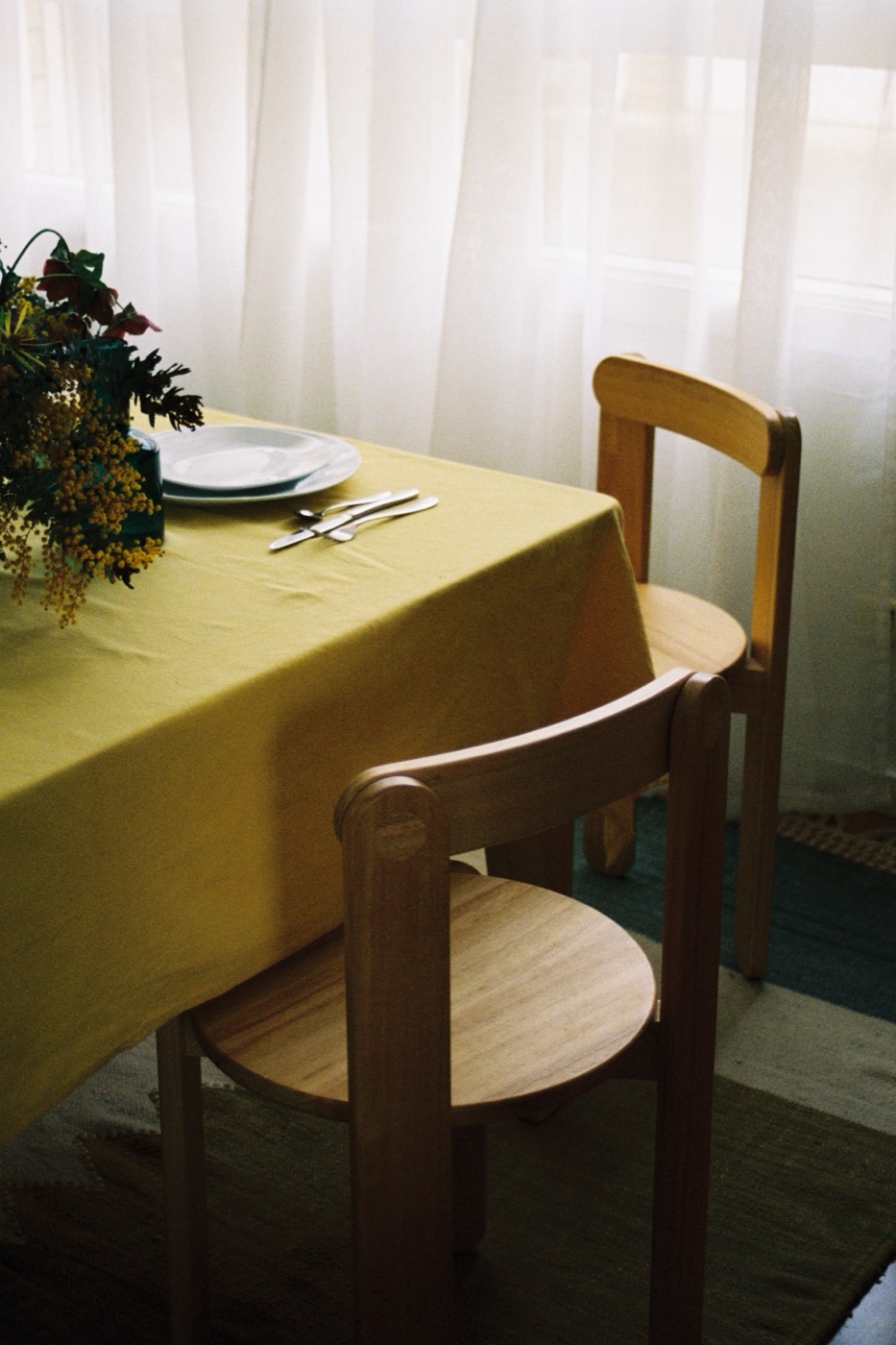 Yellow tablecloth with wooden chairs and a floral centrepiece