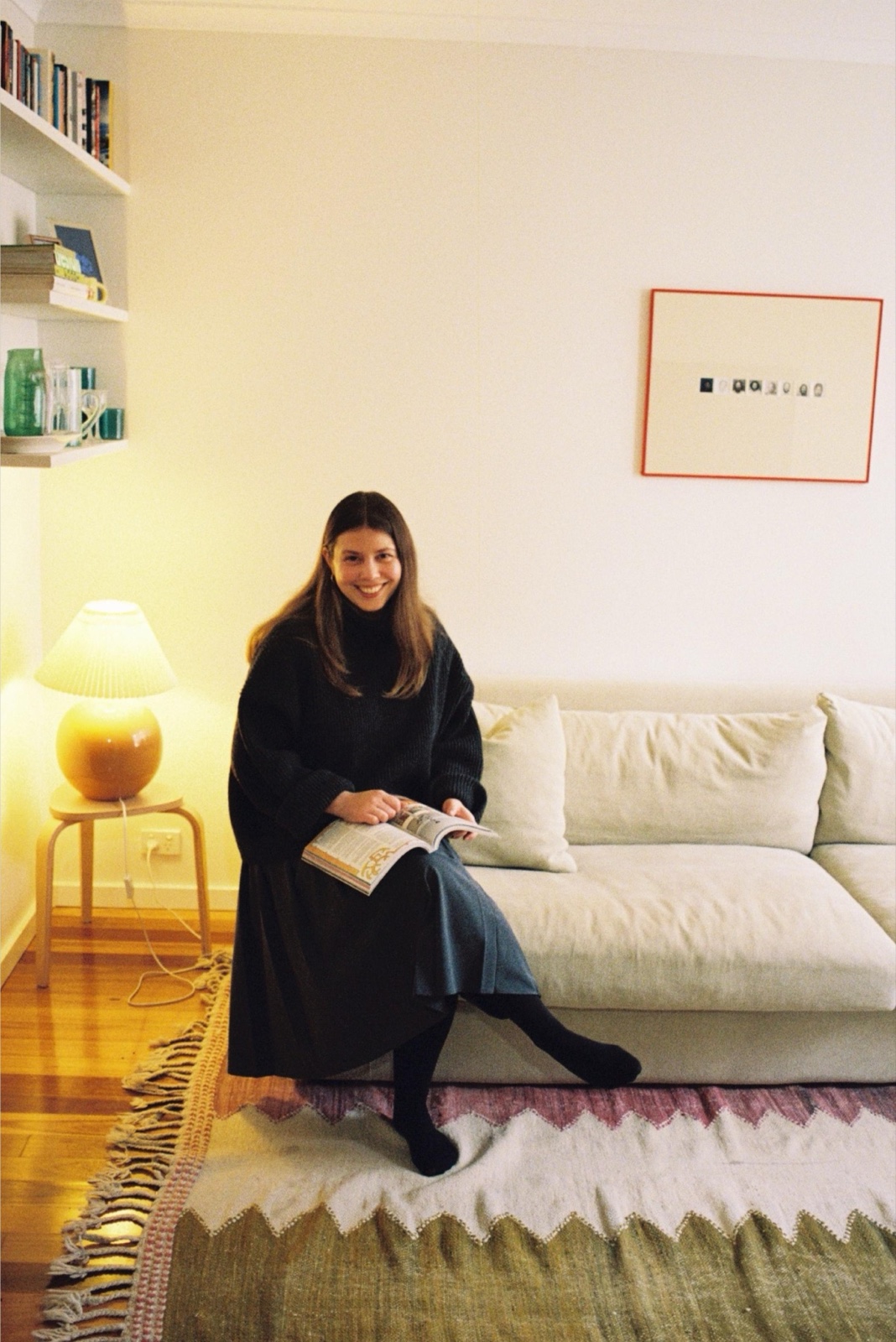 Portrait of Alice Vanderwey seated on a sofa reading a magazine