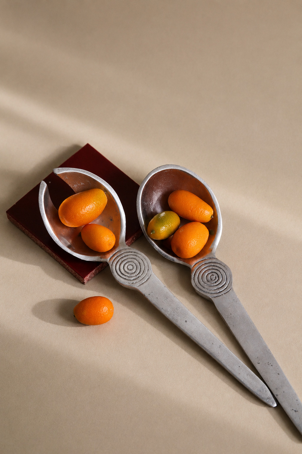 Vintage aluminium spoons holding kumquats