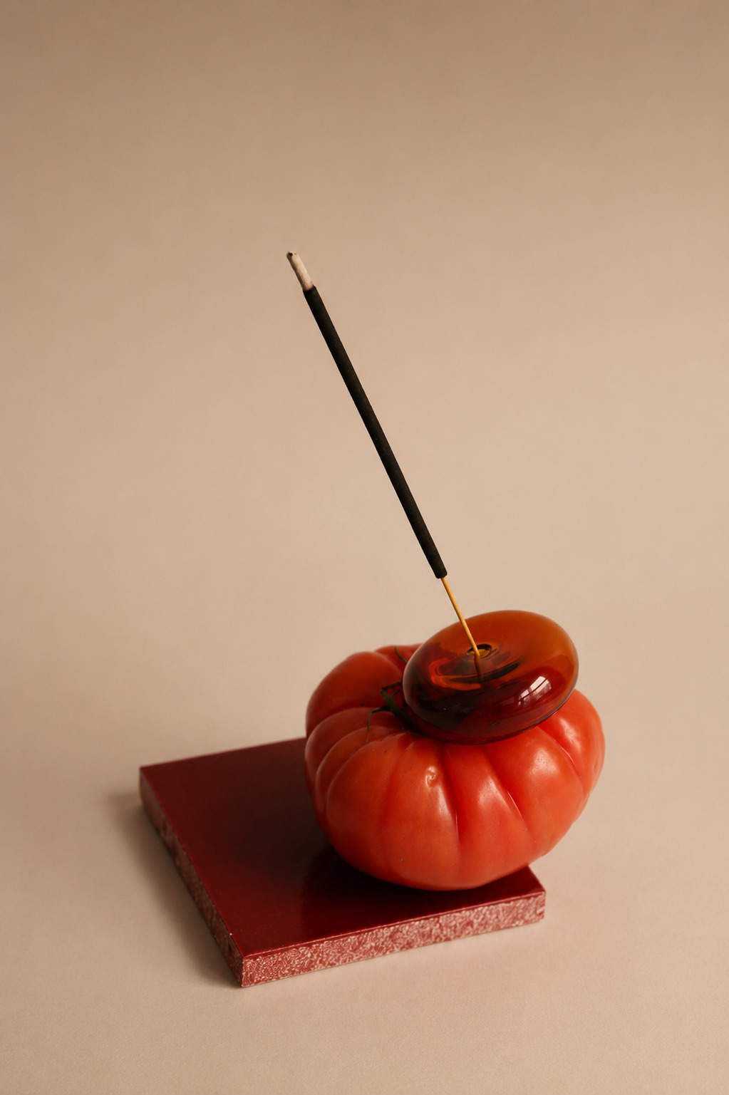 Incense stick and amber glass dish resting on a heirloom tomato